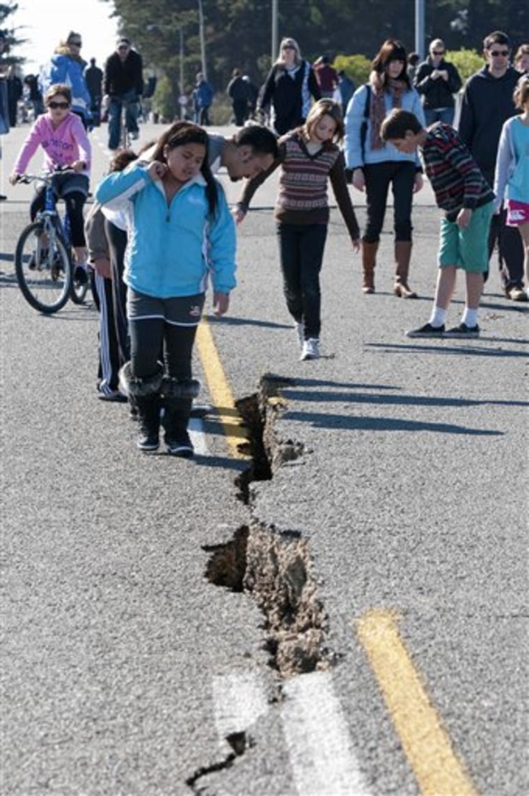 People inspect a crack caused in the South Brighton Bridge approach in Christchurch, New Zealand, Saturday, Sept. 4 2010. A powerful 7.1-magnitude earthquake struck much of New Zealand's South Island early Saturday and caused widespread damage, but there were just two reports of serious injuries. (AP Photo/NZPA, David Alexander) ** NEW ZEALAND OUT **